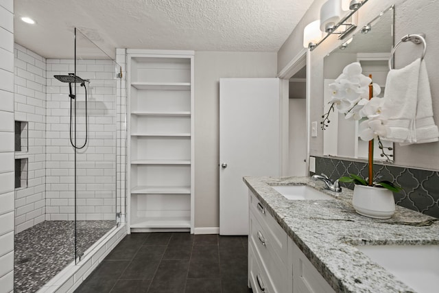 bathroom featuring tasteful backsplash, walk in shower, vanity, a textured ceiling, and tile patterned flooring