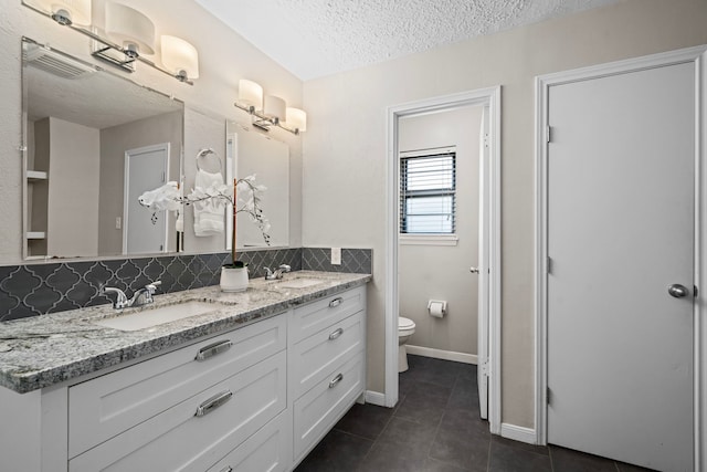 bathroom with vanity, tile patterned flooring, toilet, a textured ceiling, and tasteful backsplash