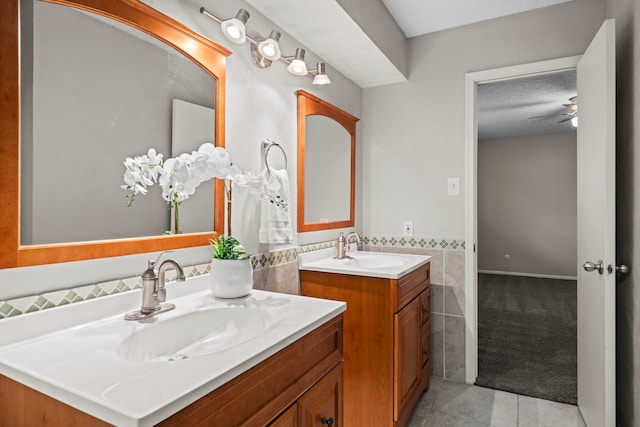 bathroom featuring vanity, tile patterned floors, ceiling fan, a textured ceiling, and tile walls