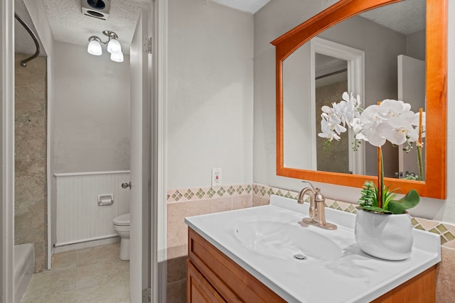 bathroom with tile patterned floors, vanity, toilet, and a textured ceiling