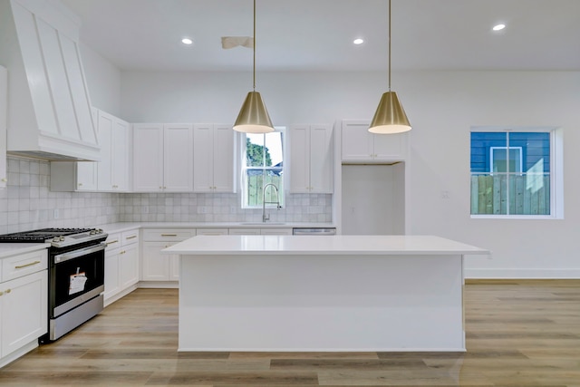 kitchen with white cabinetry, decorative light fixtures, a center island, and gas stove