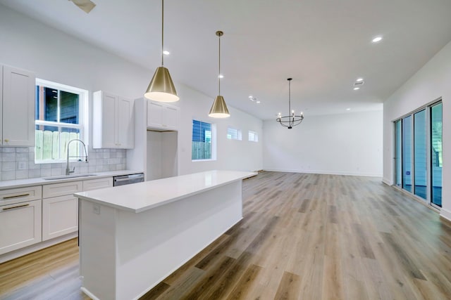 kitchen featuring white cabinets, hanging light fixtures, a healthy amount of sunlight, and light wood-type flooring