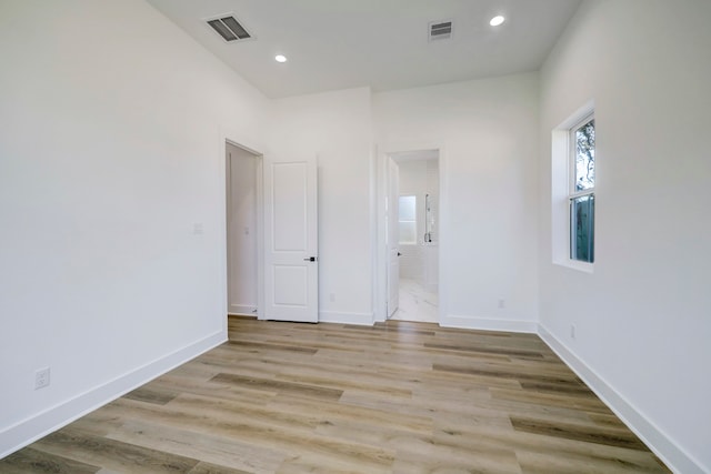 unfurnished bedroom featuring light wood-type flooring and ensuite bath