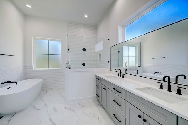 bathroom with tile walls, vanity, and independent shower and bath