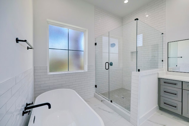 bathroom with tile walls, vanity, and shower with separate bathtub