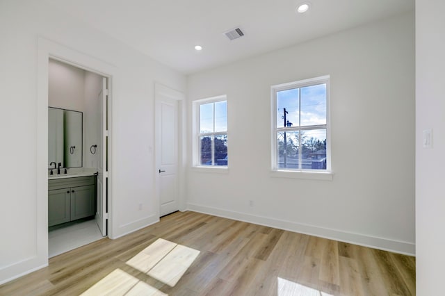 unfurnished bedroom with sink, light hardwood / wood-style floors, and ensuite bath