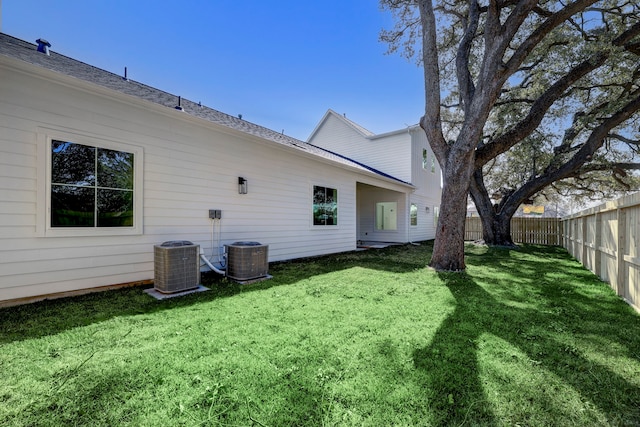 rear view of house featuring central AC unit and a lawn