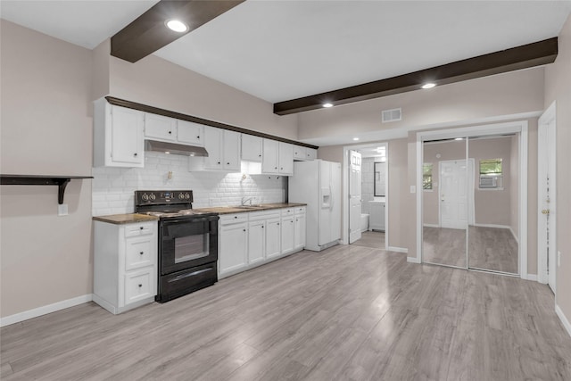 kitchen with light hardwood / wood-style flooring, black / electric stove, white cabinetry, beam ceiling, and white fridge with ice dispenser