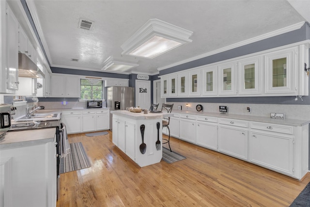 kitchen with a kitchen breakfast bar, white cabinets, light wood-type flooring, stainless steel fridge with ice dispenser, and a center island