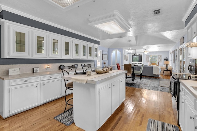 kitchen featuring a breakfast bar area, ceiling fan, white cabinets, and a center island