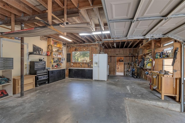 garage with white fridge with ice dispenser, electric panel, and a workshop area