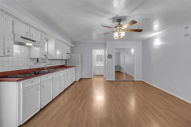 kitchen featuring white refrigerator, tasteful backsplash, light hardwood / wood-style flooring, and white cabinetry