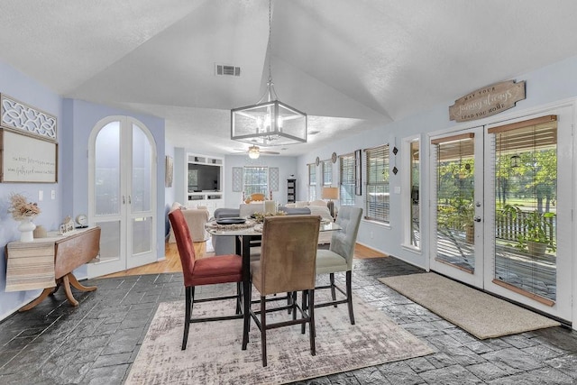 dining space with an inviting chandelier, french doors, and vaulted ceiling