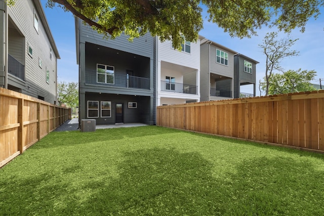 rear view of property featuring central AC and a yard