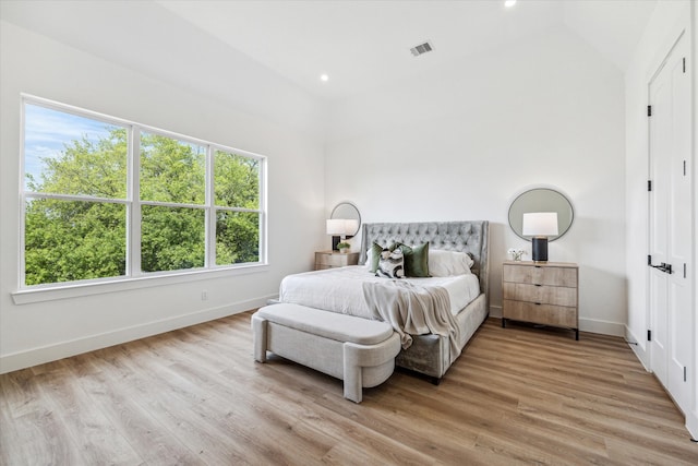 bedroom with light wood-type flooring and vaulted ceiling