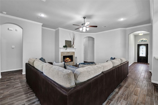 living room featuring a tiled fireplace, ornamental molding, and ceiling fan