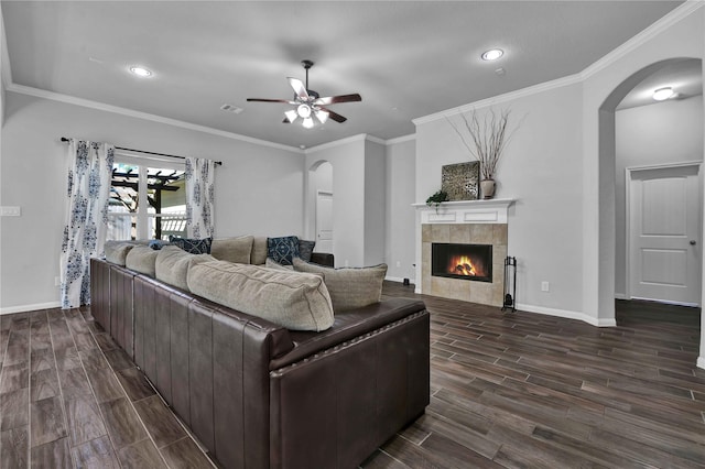 living room with crown molding, ceiling fan, and a fireplace