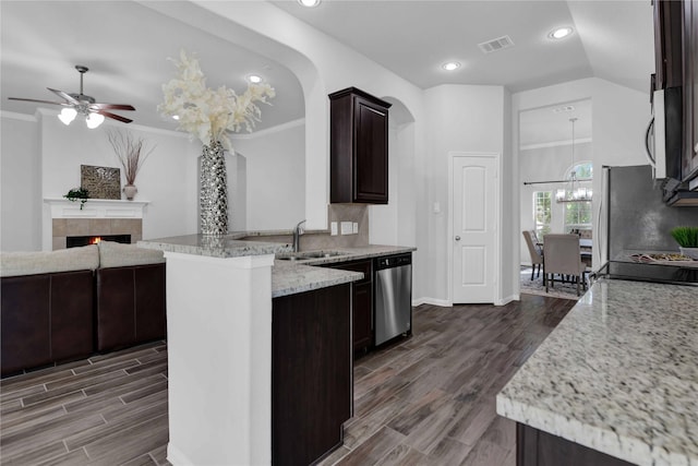 kitchen with lofted ceiling, sink, light stone counters, appliances with stainless steel finishes, and a fireplace