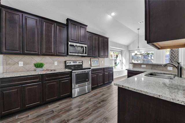 kitchen with sink, vaulted ceiling, pendant lighting, stainless steel appliances, and backsplash