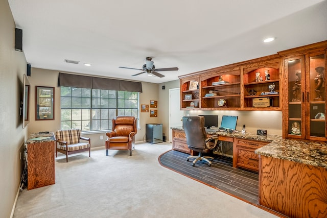 office area with dark colored carpet, built in desk, and ceiling fan