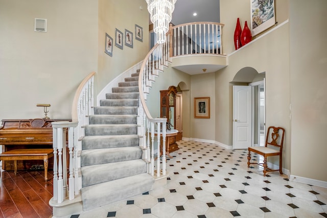 entrance foyer with a towering ceiling, wood-type flooring, and an inviting chandelier