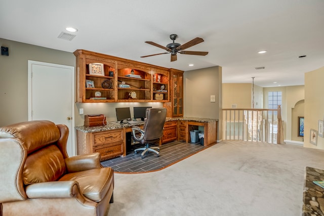 office space with built in desk, ceiling fan, and dark colored carpet