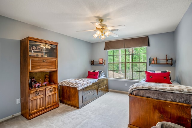 carpeted bedroom with ceiling fan and a textured ceiling