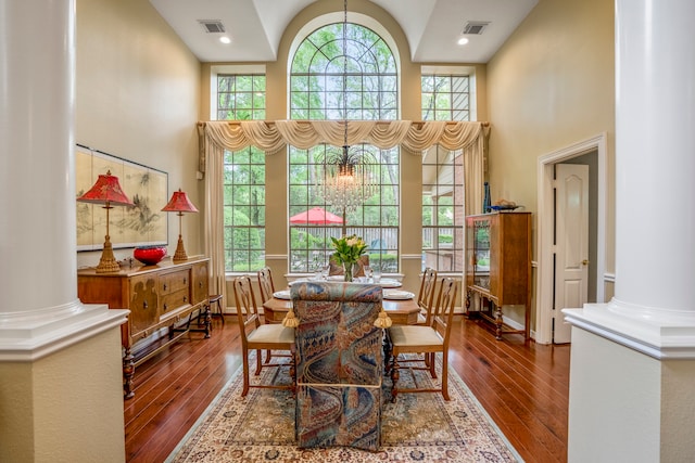 dining room featuring ornate columns, high vaulted ceiling, and hardwood / wood-style floors