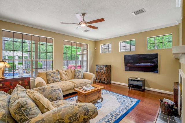 living room with a wealth of natural light, ceiling fan, crown molding, and hardwood / wood-style flooring