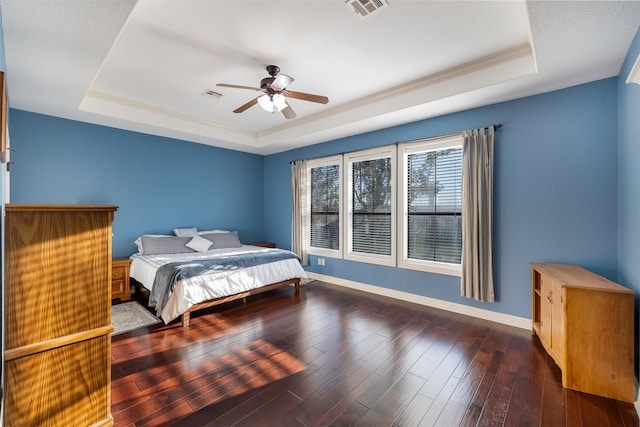 bedroom featuring dark wood-type flooring, ceiling fan, and a raised ceiling