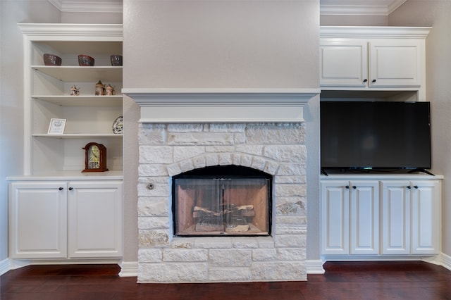 unfurnished living room with ornamental molding, built in features, a stone fireplace, and dark hardwood / wood-style floors