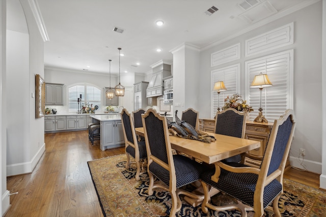 dining space with crown molding and light hardwood / wood-style flooring