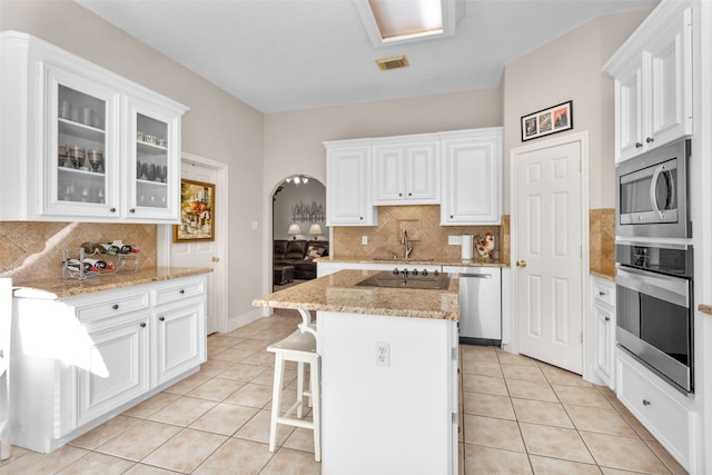 kitchen featuring appliances with stainless steel finishes, white cabinetry, a kitchen island, and tasteful backsplash