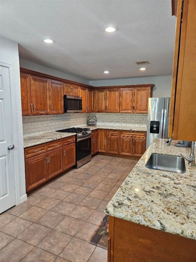 10438 Lauren Creek Dr, Baytown, TX 77523 - kitchen featuring stainless steel appliances, a sink, tasteful backsplash, brown cabinetry, and light stone countertops