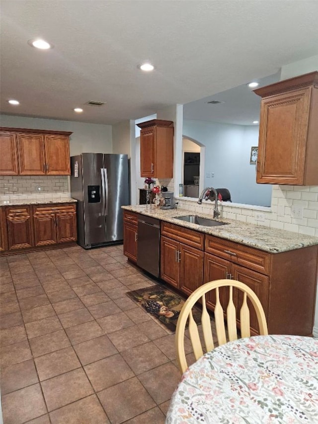 10438 Lauren Creek Dr, Baytown, TX 77523 - kitchen featuring appliances with stainless steel finishes, a sink, decorative backsplash, brown cabinetry, and recessed lighting