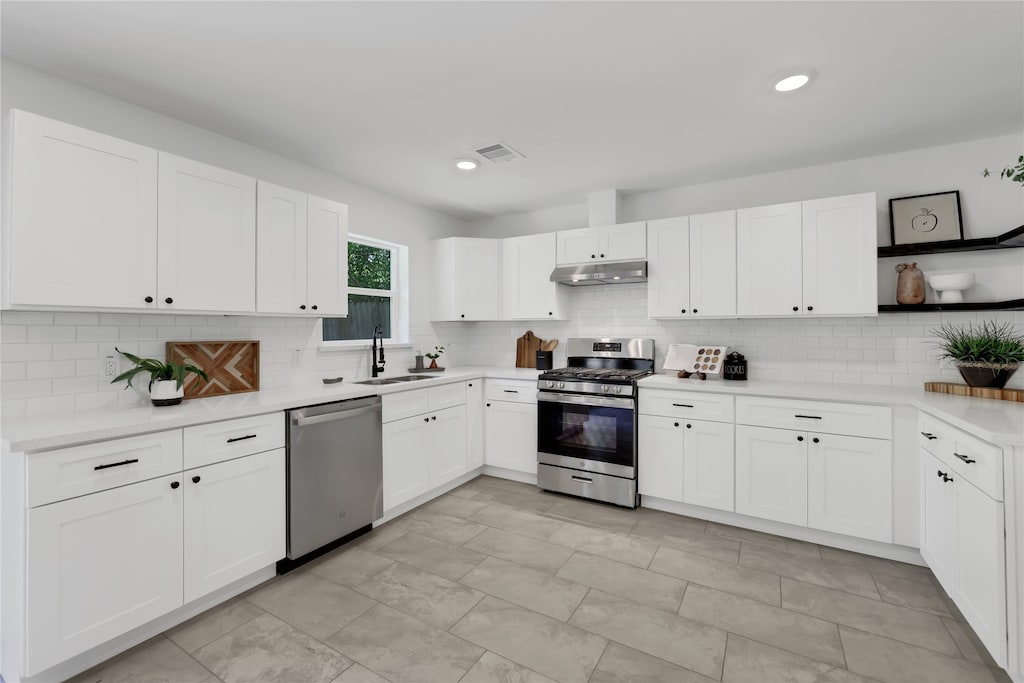 kitchen with backsplash, white cabinets, sink, and stainless steel appliances