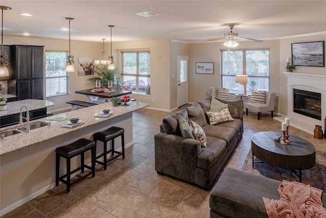 living room featuring sink, ceiling fan with notable chandelier, and plenty of natural light