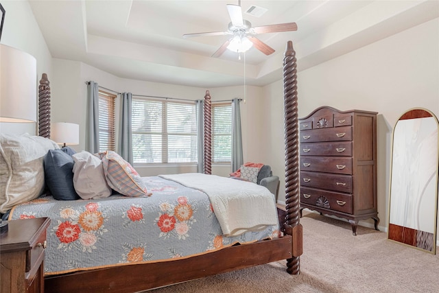 carpeted bedroom featuring ceiling fan and a tray ceiling