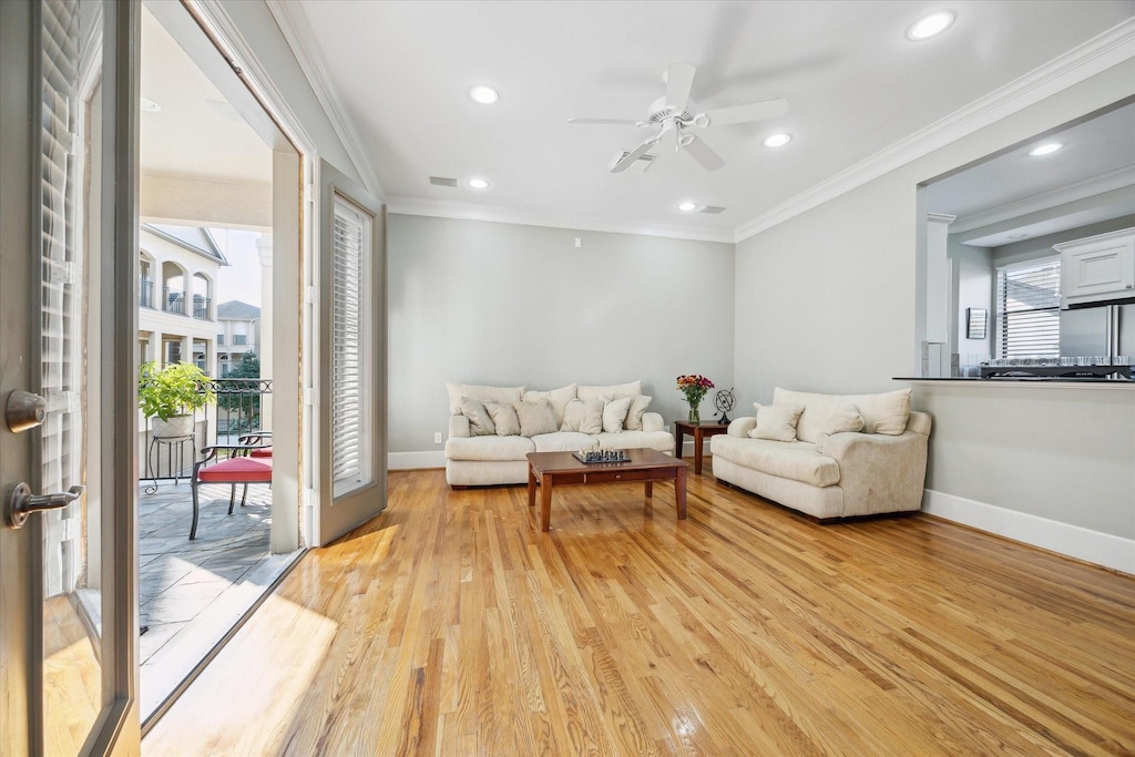 living room with plenty of natural light, ceiling fan, ornamental molding, and light hardwood / wood-style flooring