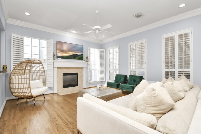 living room featuring a fireplace, light wood-type flooring, ceiling fan, and ornamental molding