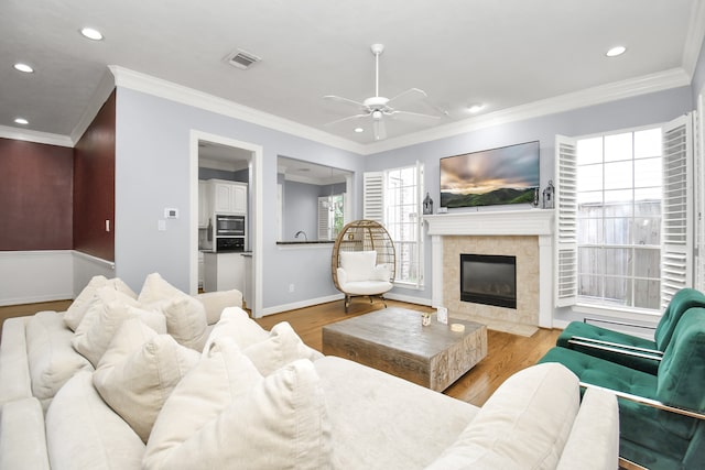 living room featuring light wood-type flooring, crown molding, and a tile fireplace