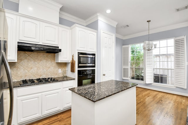 kitchen featuring white cabinetry, dark stone countertops, light hardwood / wood-style floors, decorative light fixtures, and appliances with stainless steel finishes