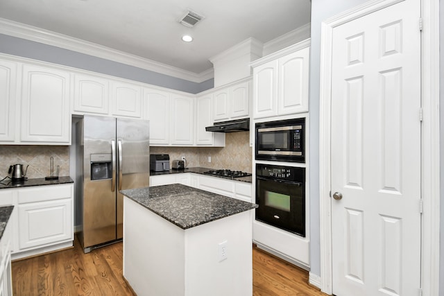 kitchen with a center island, dark stone counters, white cabinets, light hardwood / wood-style floors, and stainless steel appliances