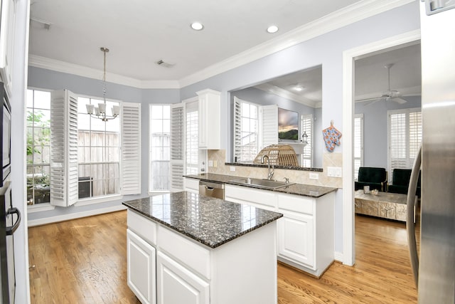 kitchen featuring sink, light hardwood / wood-style flooring, dark stone countertops, a kitchen island, and white cabinetry