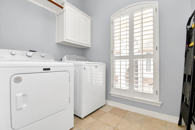 laundry room with cabinets, light tile patterned floors, and washer and dryer