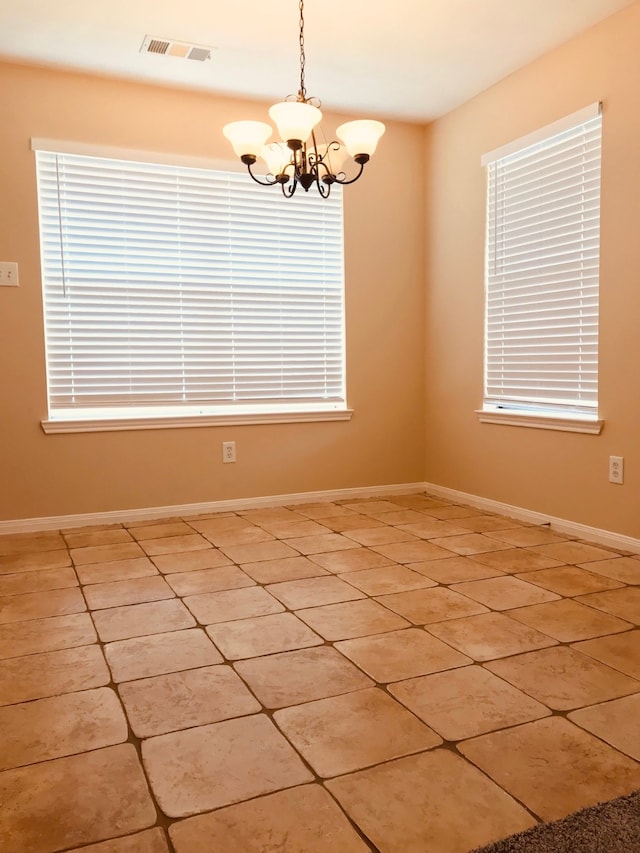 tiled empty room with an inviting chandelier