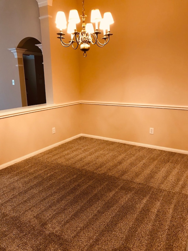 empty room featuring ornate columns, an inviting chandelier, and carpet