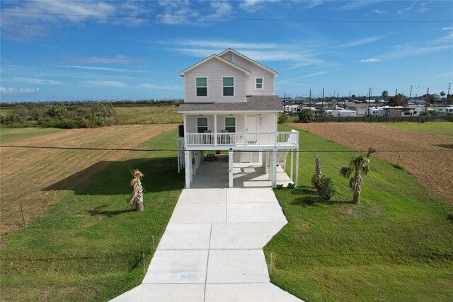 18103 Shaman Dr, Galveston, TX 77554 - coastal inspired home featuring a carport, concrete driveway, a front lawn, a shingled roof, and covered porch