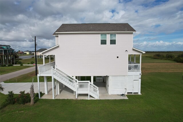 18103 Shaman Dr, Galveston, TX 77554 - back of house featuring a patio, a lawn, and a shingled roof