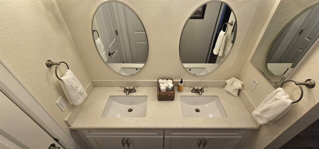 18103 Shaman Dr, Galveston, TX 77554 - bathroom featuring double vanity and a textured wall